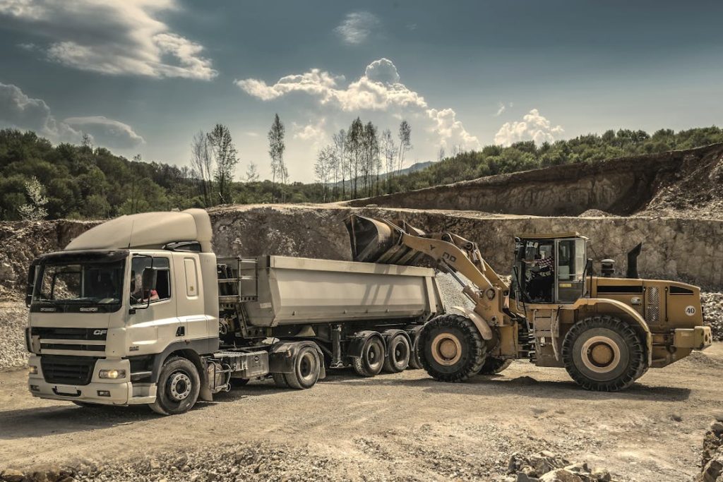 Front loader beside dump truck at construction site - aggregate factoring services